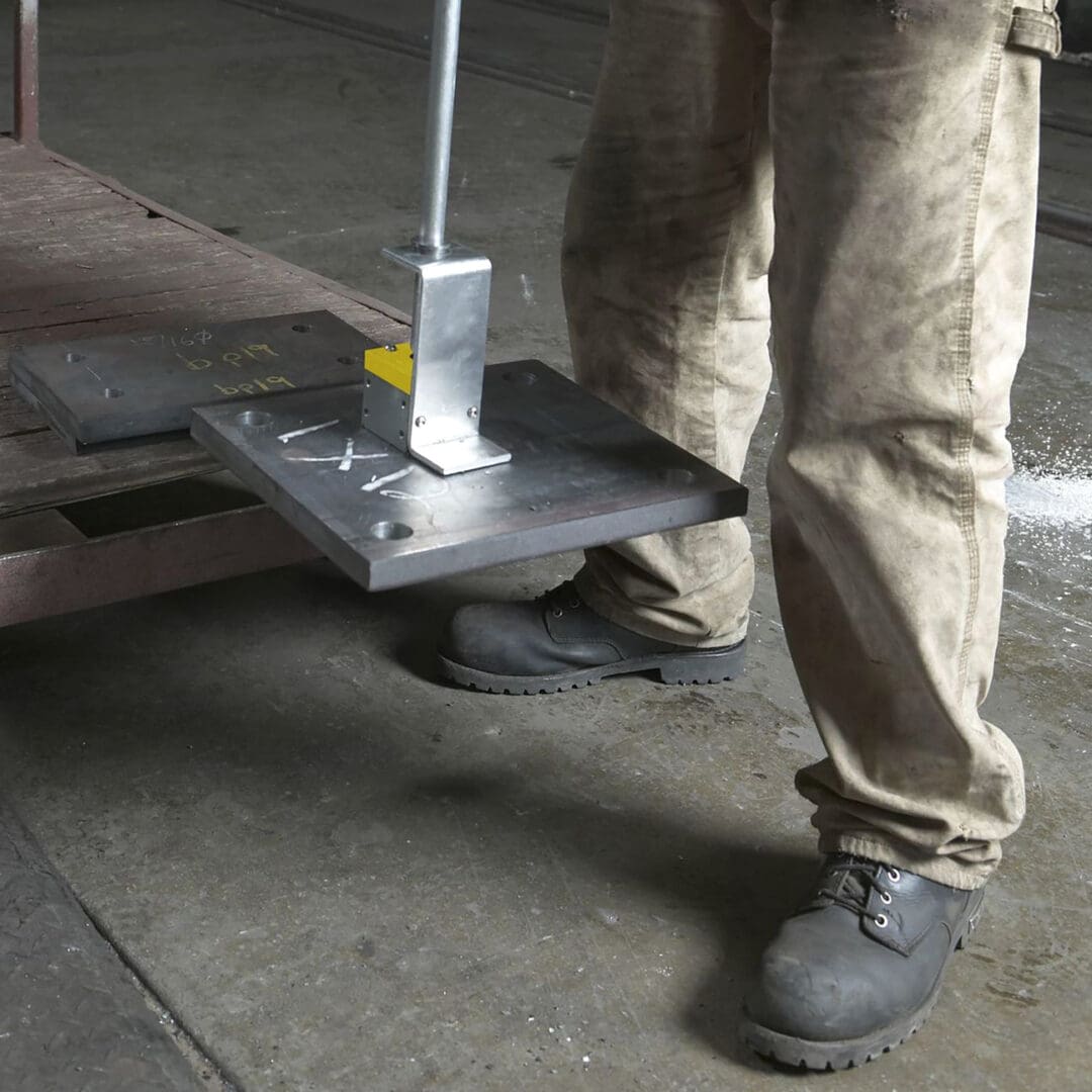 Person using magnetic lifter on metal sheet.