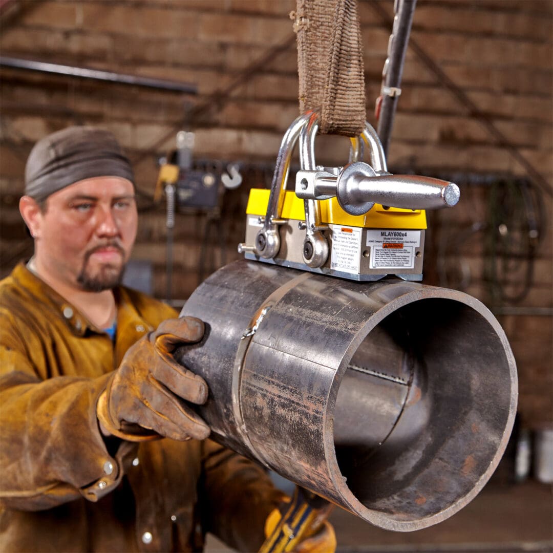 Worker handling large metal pipe with magnet.
