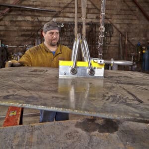 Worker operating heavy-duty lifting equipment indoors.
